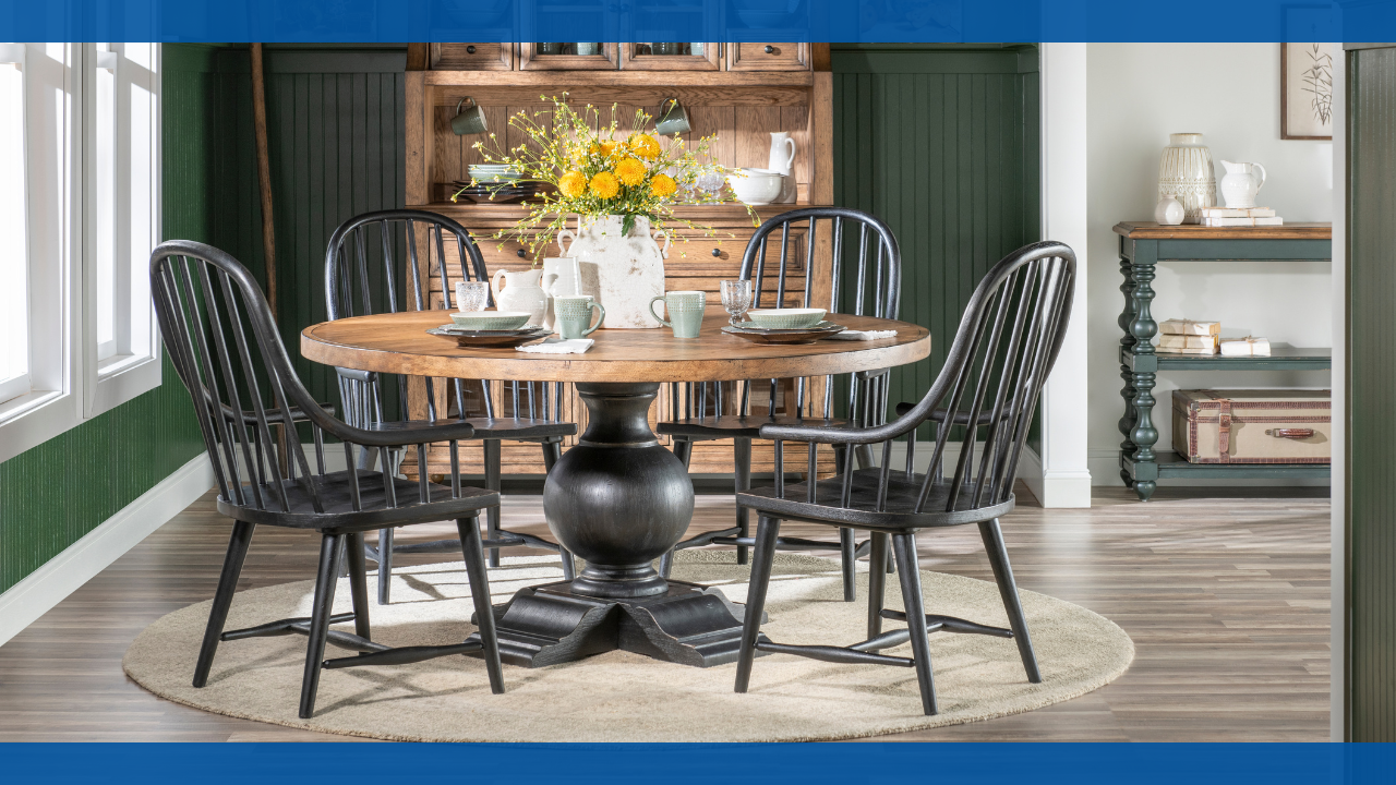 Round dining table with black chairs and a flower centerpiece in a cozy room.