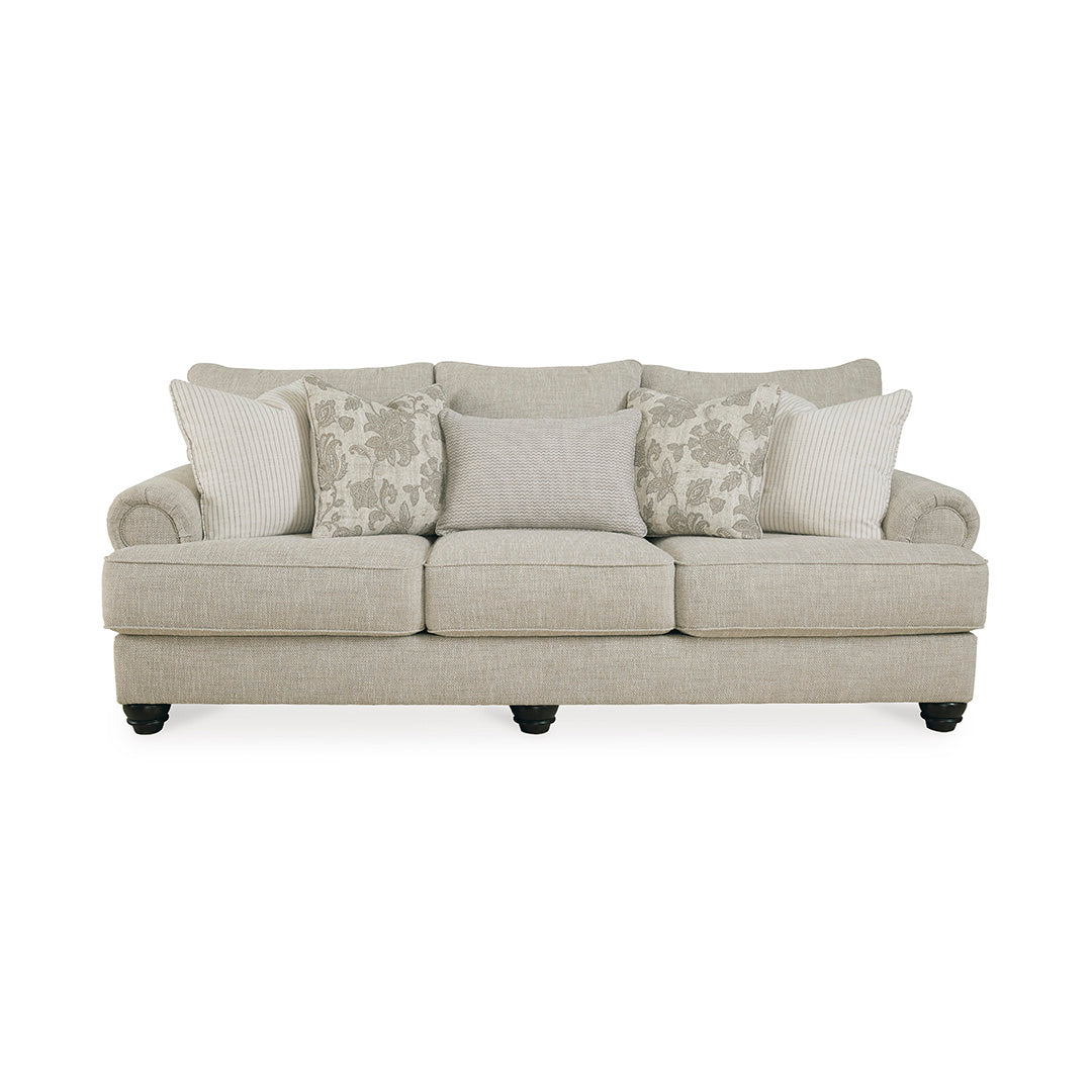 Beige sofa by ashley furniture with decorative pillows on a white background
