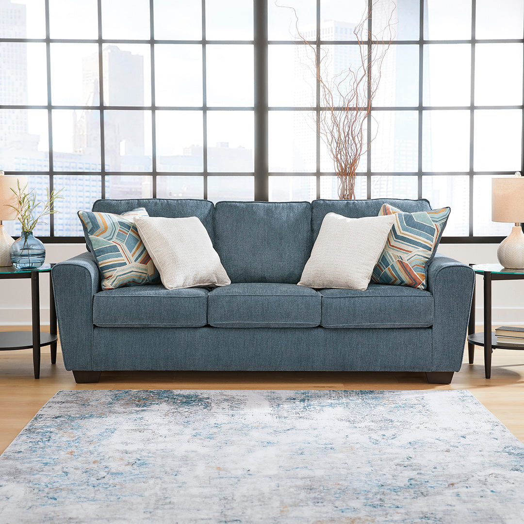 Blue sofa with decorative pillows in a living room setting