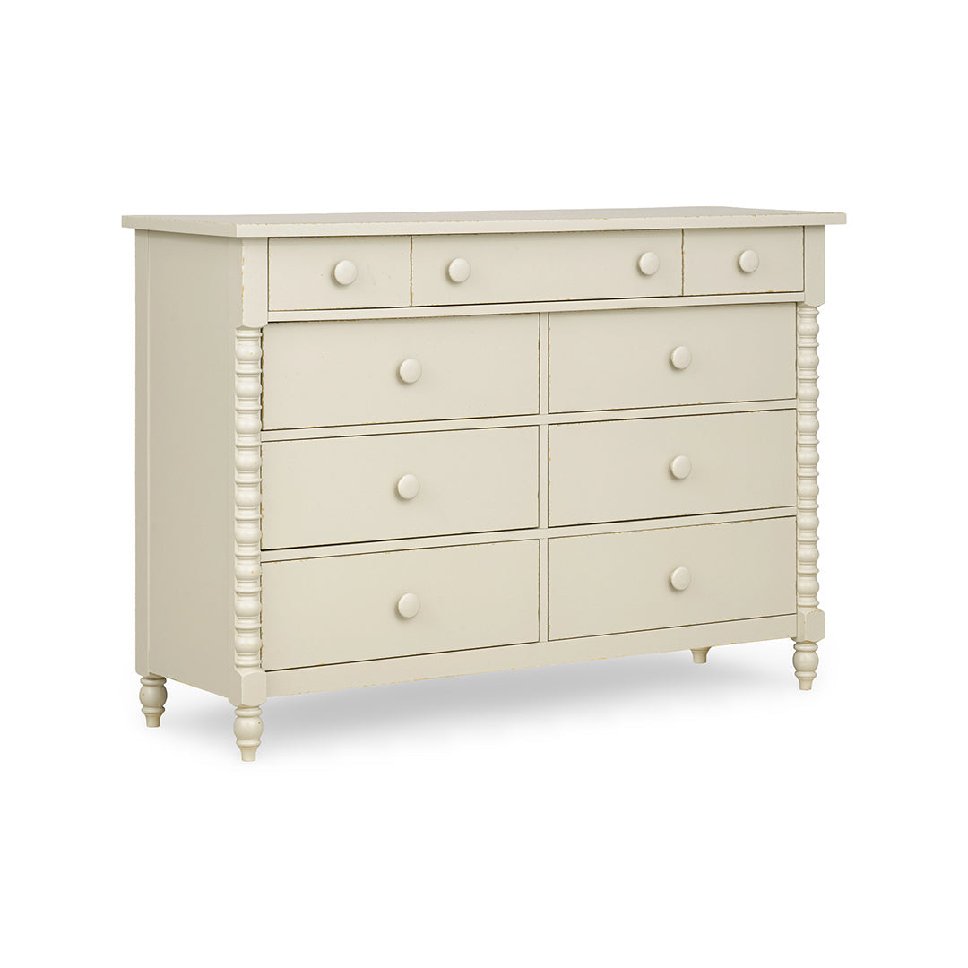 An off-white painted wooden dresser with six drawers, featuring decorative turned legs and round knobs.