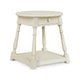 A small round side table with a single drawer, turned legs, and a lower shelf, painted in a warm cream or off-white finish