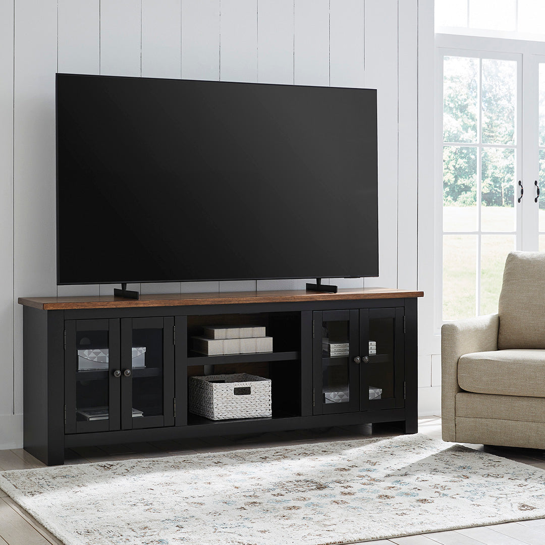 TV on a wooden stand in a living room with a couch and large window.