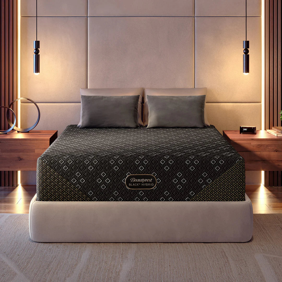 Beautyrest Black Hybrid mattress on a beige upholstered bed frame with warm bedroom lighting