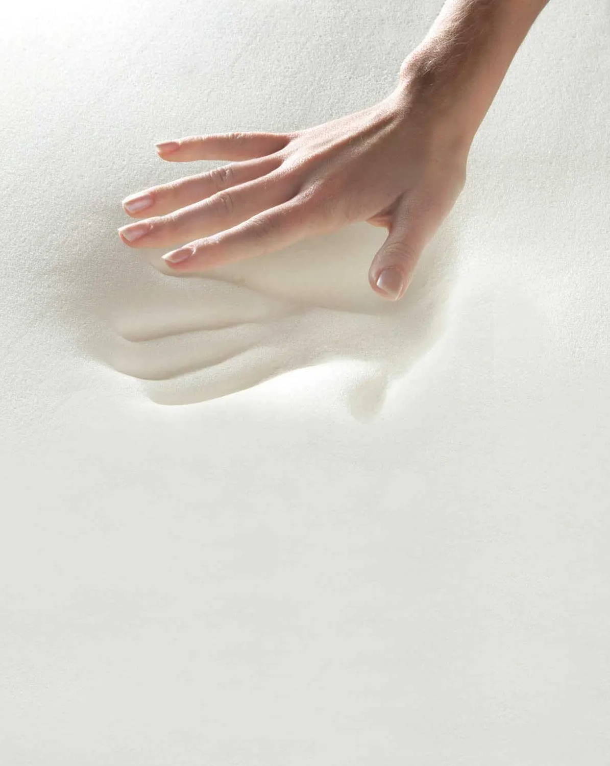Hand pressing into white memory foam leaving a deep imprint that slowly rebounds
