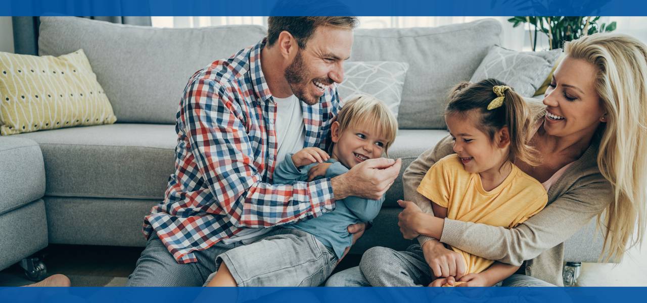 A family playing together on a couch, smiling and enjoying time.