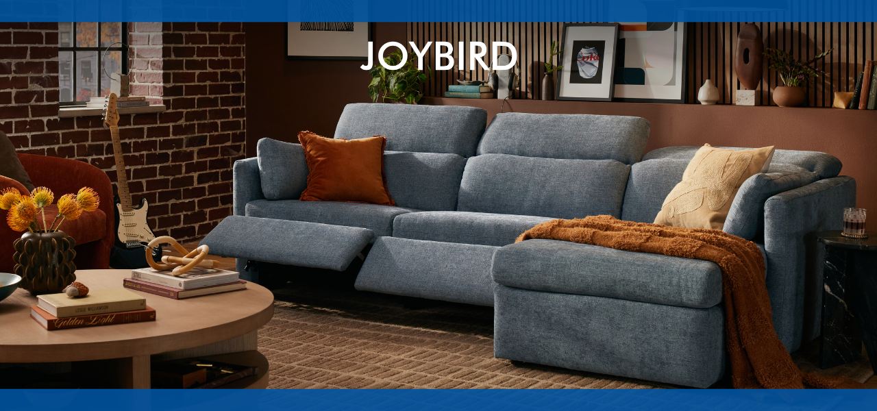 A modern blue sofa by joybird with decorative pillows and a cozy throw blanket.