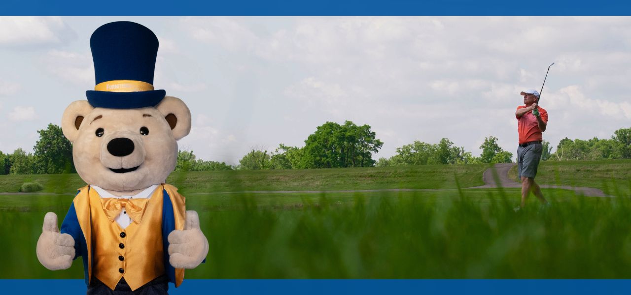 A bear mascot stands beside a golfer on a green field.