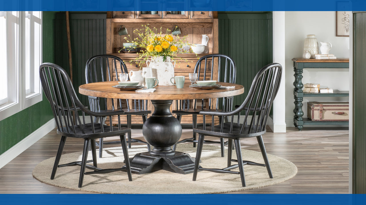 Round dining table with black chairs and a flower centerpiece in a cozy room.