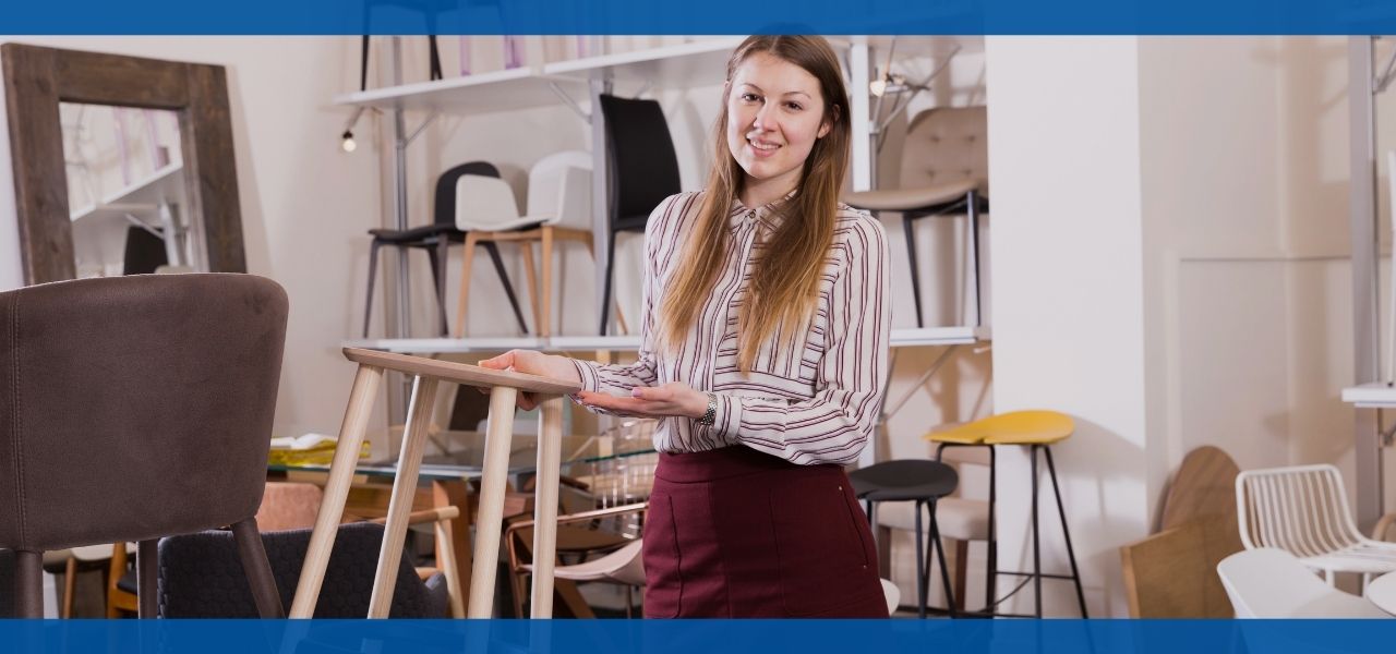 Smiling woman standing in a furniture store, showcasing various items.
