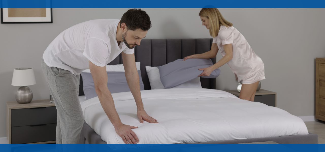 A couple making the bed together in a modern bedroom.