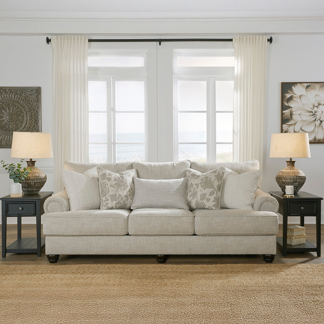 Living room with a beige sofa, floral-patterned pillows, and two lamps on side tables.