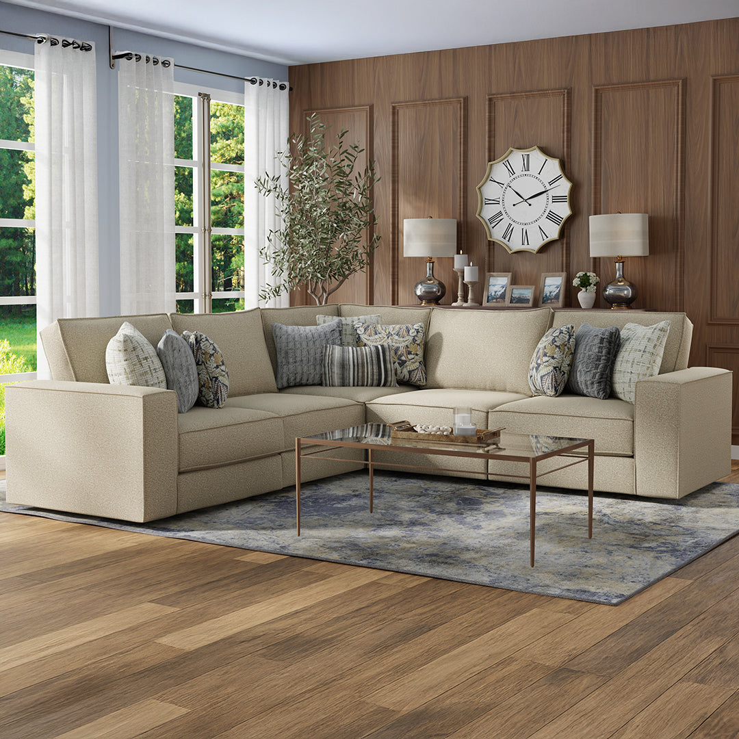 Beige sectional sofa in a living room with wooden walls and a clock.