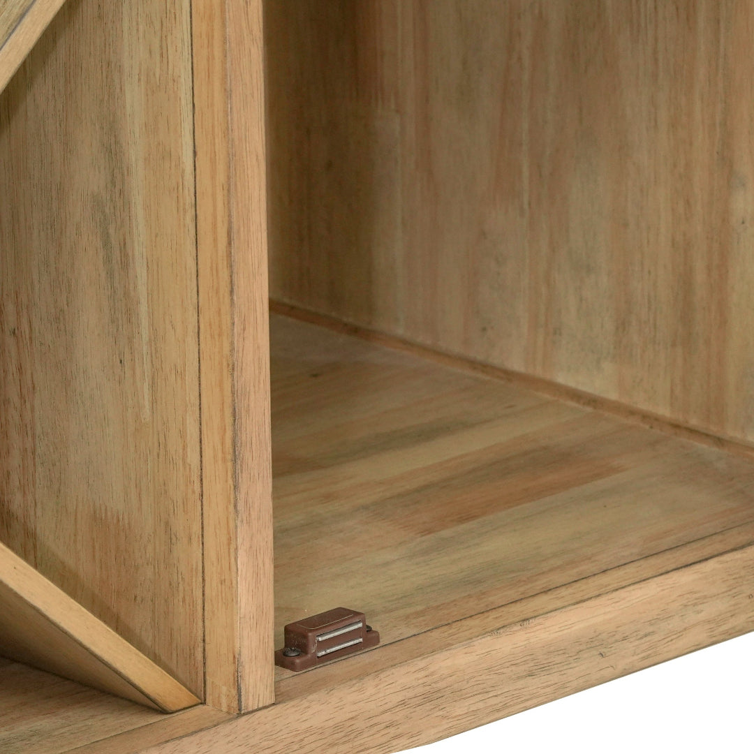 Close-up of a wooden cabinet or shelf with a slanted door, showing the wood grain, interior corner, and a small metal hinge near the bottom.