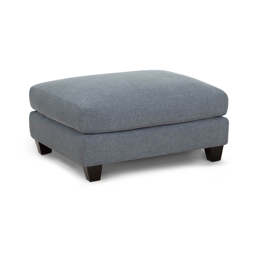 Gray upholstered ottoman with dark wood legs on a white background