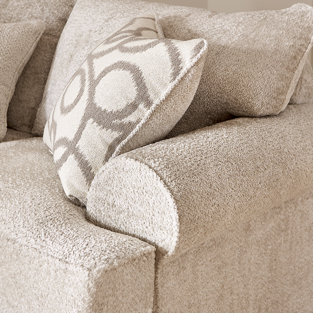Close-up of a textured beige sofa by Michael Nicholas with a patterned pillow