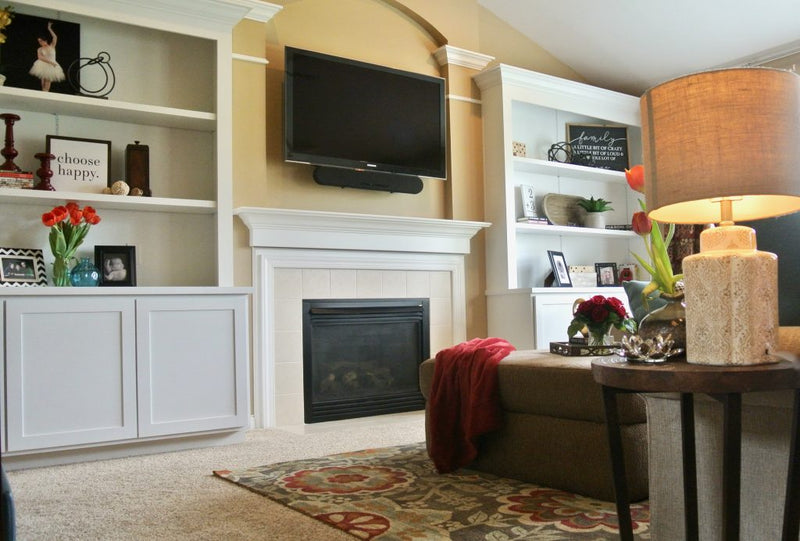 Living room layout featuring a television mounted above a fireplace mantel flanked by built-in shelving and seating