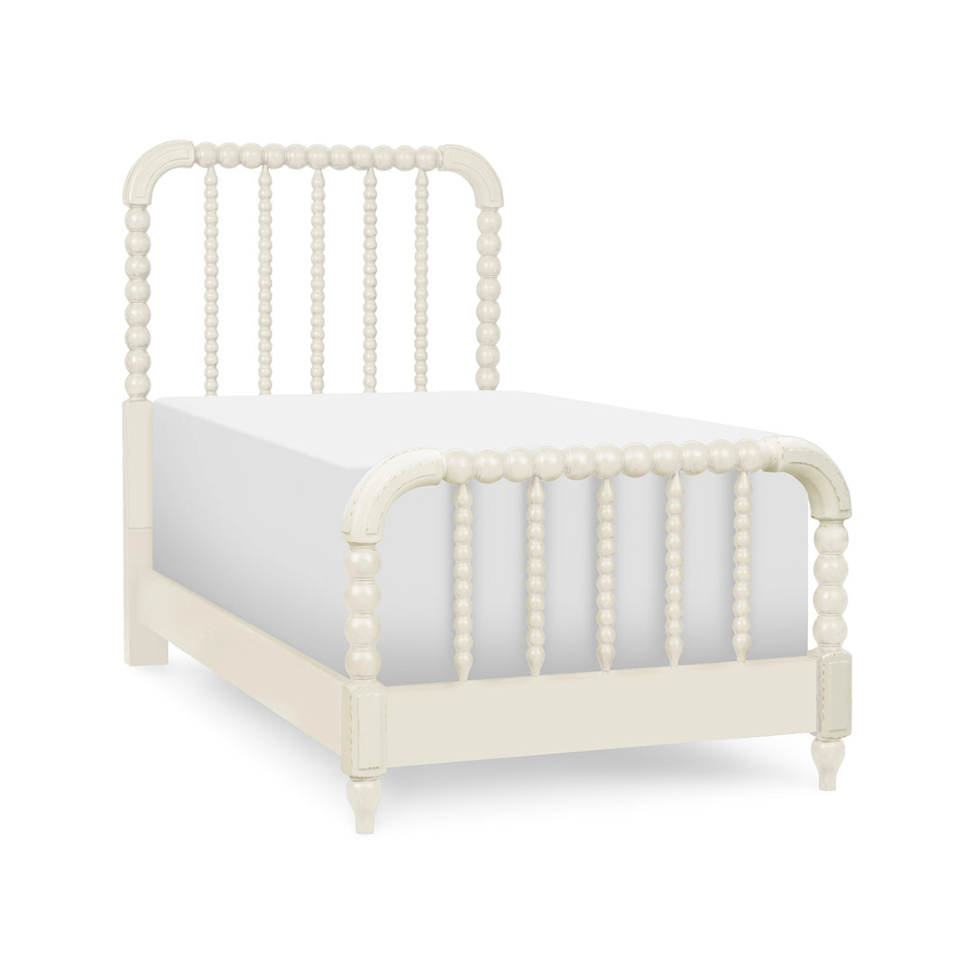 An off-white wooden bed frame with a spindle headboard and footboard, shown with a white mattress.