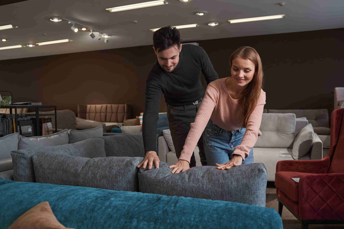 Couple in a Furniture Fair showroom testing upholstery cushions and build quality in person