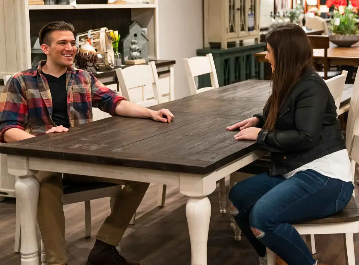Couple sitting at dining table in Furniture Fair showroom testing room clearance