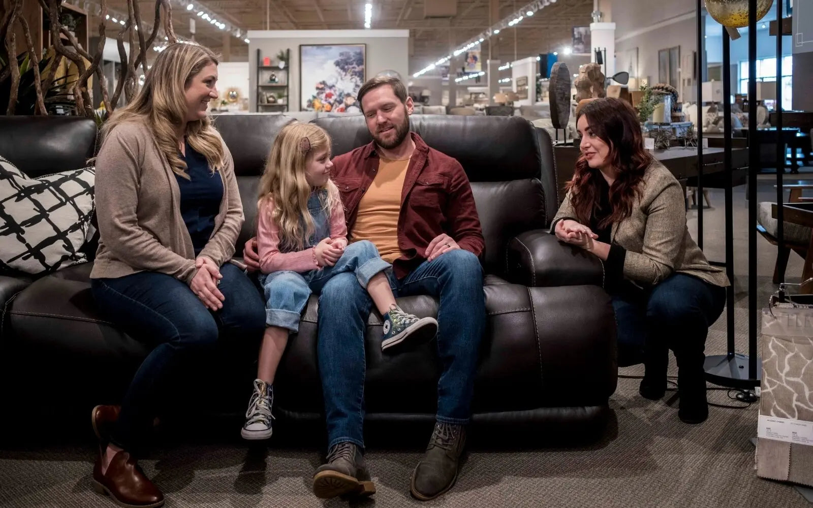 Family shopping for furniture together in a store showroom, comparing options in person