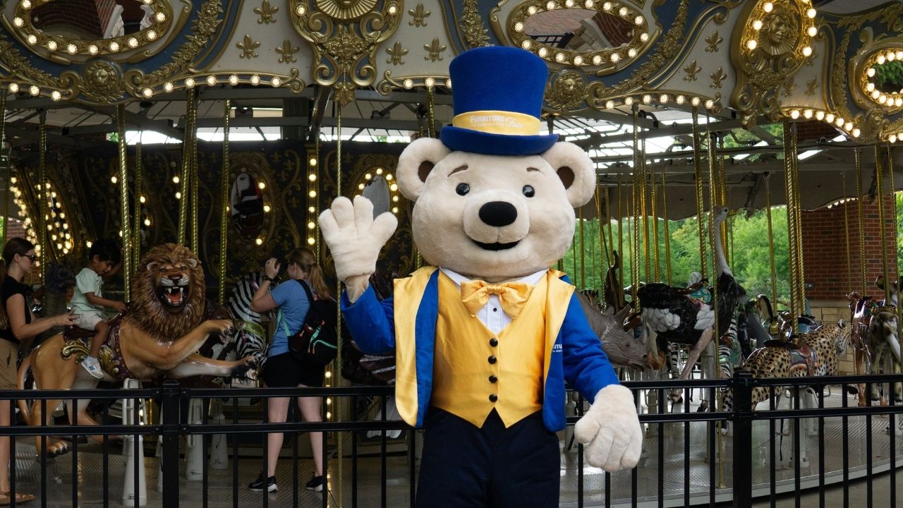 Share Bear mascot handing out plushies to children at a zoo carousel