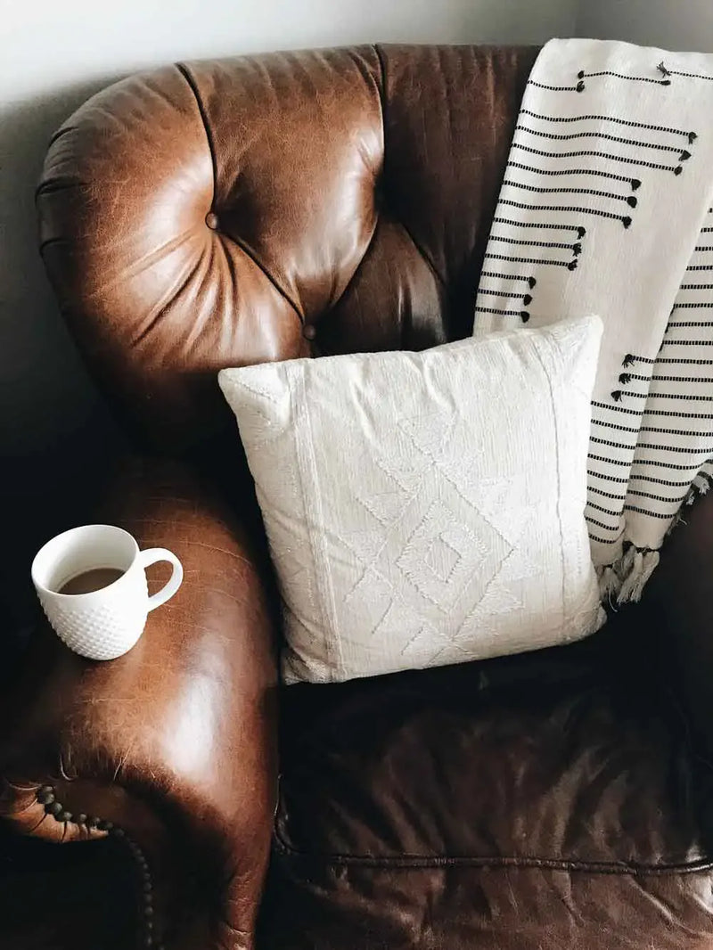 Brown tufted Chesterfield leather sofa and loveseat arranged in a living room with cowhide rug