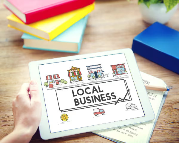Tablet displaying a local business concept illustration with storefront icons and an upward trend arrow