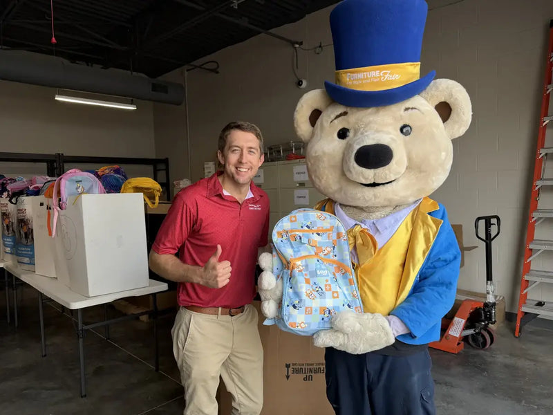 Marketing Director Craig Daniels giving a thumbs up beside Share Bear the mascot holding a packed backpack for Operation Backpack 2026