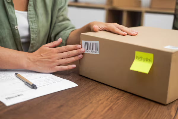 Person preparing a cardboard shipping box with a RETURN label for sending furniture back