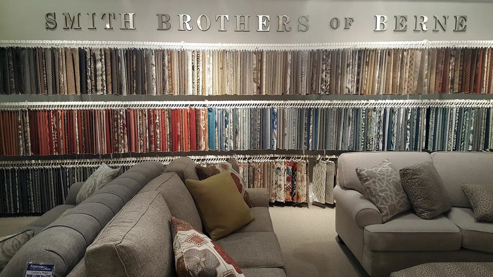 Smith Brothers fabric wall display at Furniture Fair showroom showing hundreds of upholstery swatch options