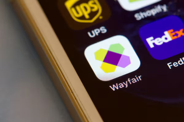 Wayfair mobile app icon on a smartphone screen surrounded by shipping app icons