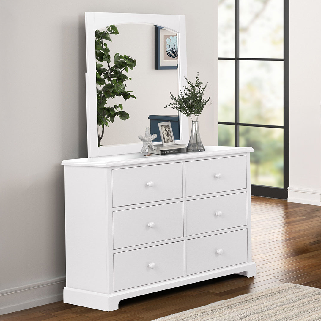 White dresser with mirror in a room with a window and plant