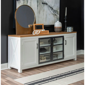 Franklin Entertainment Console. Simple farmhouse details and motifs create visual interest in a modern way and without feeling too cluttered. Harvest Oak top on quartered white oak veneer sits atop the Natural White painted base. 4 doors, two with glass fronts. Matte Black hardware and detailing around doors.